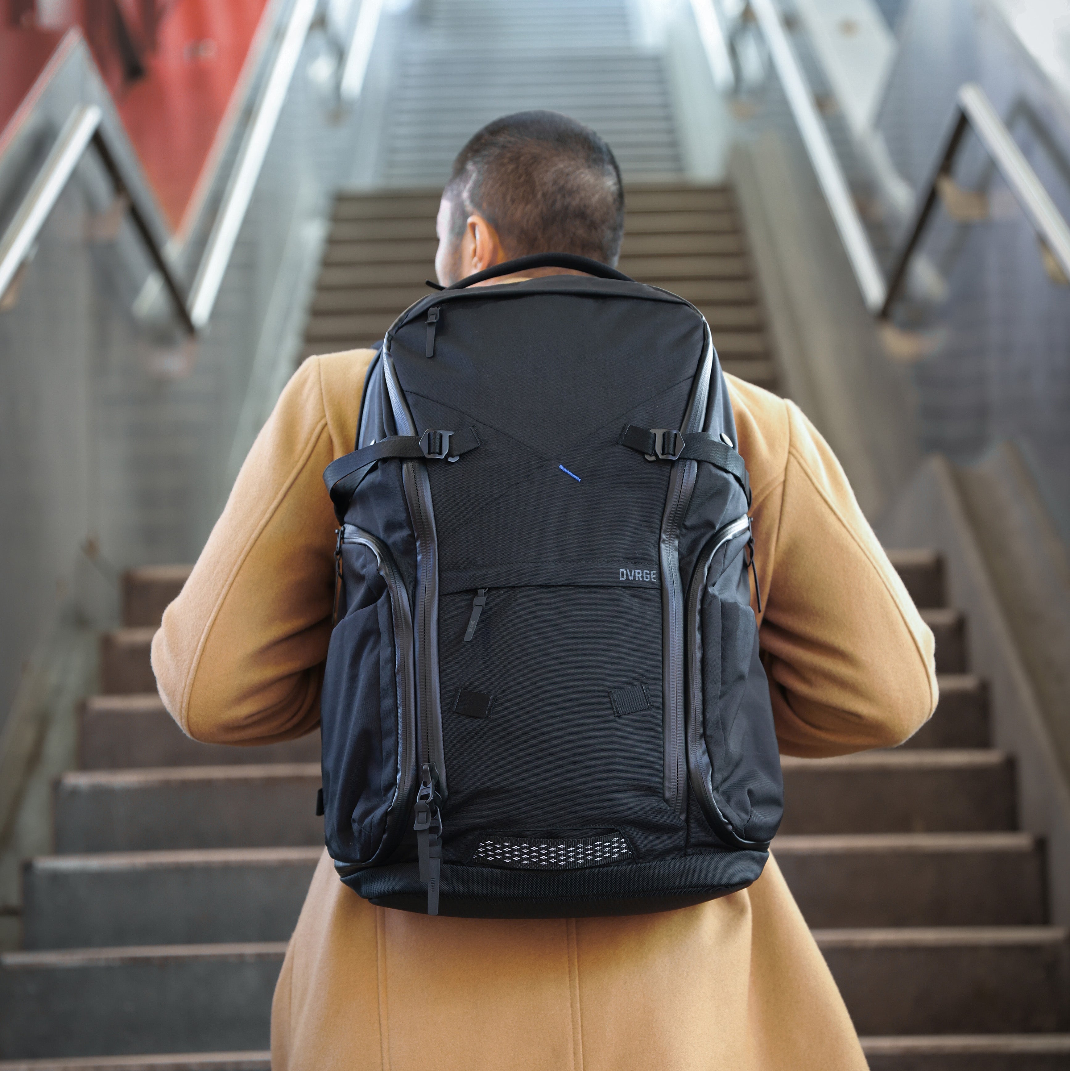 Person with a black backpack walking up stairs in an urban setting