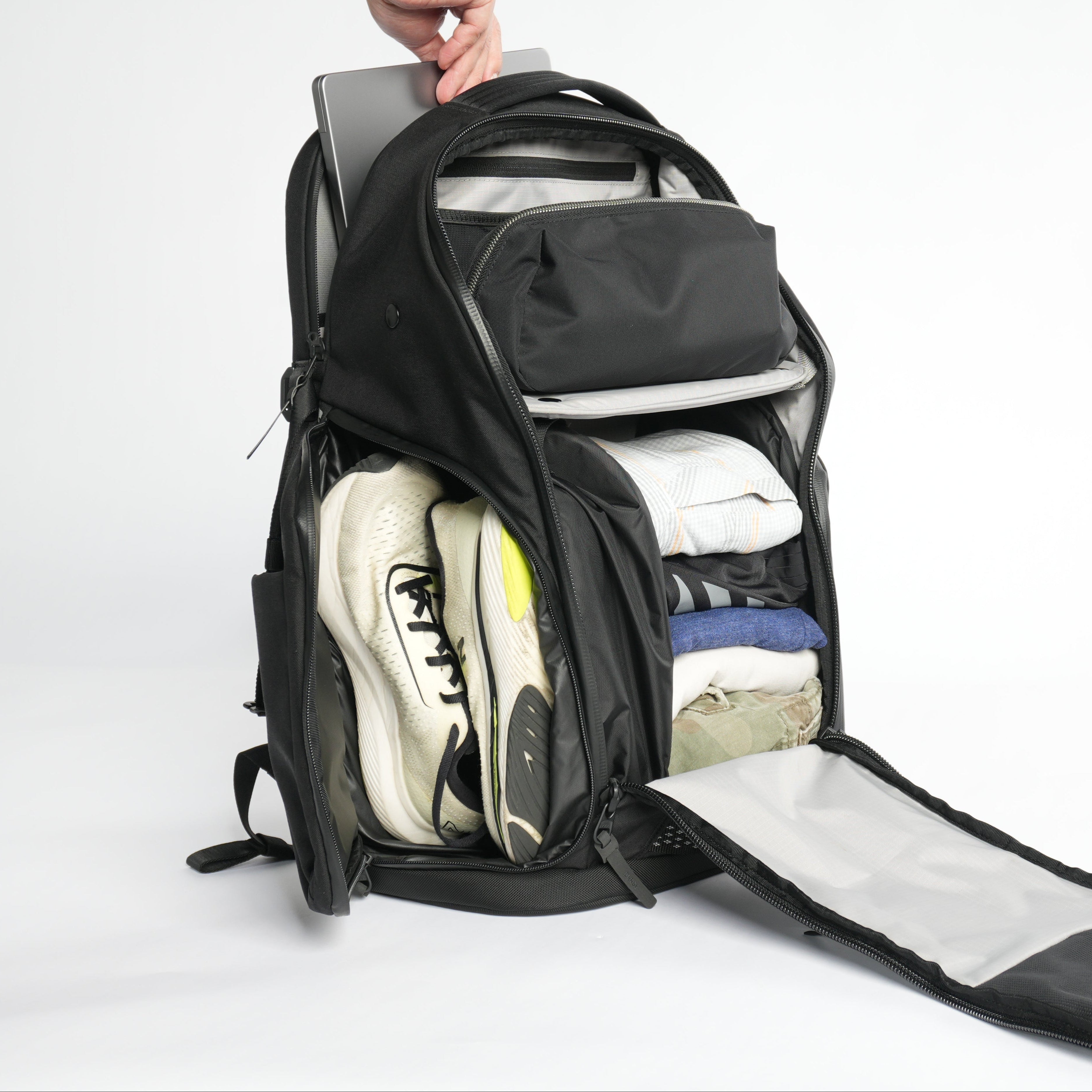Black backpack with compartments for shoes and clothes on a white background. Laptop sleeve is demonstrated