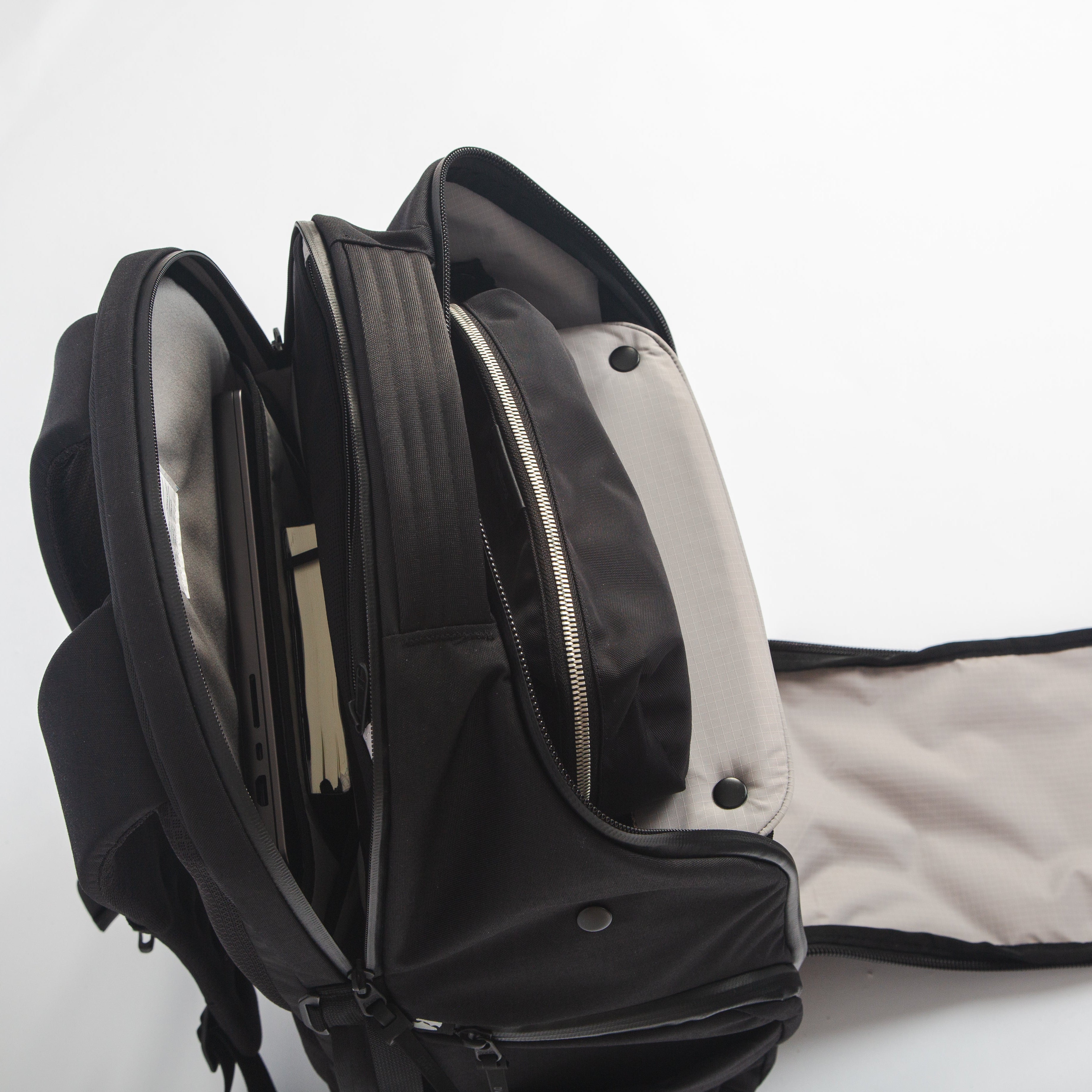 Upper zippers of DVRGE backpack opened to display laptop compartment and shelf divider