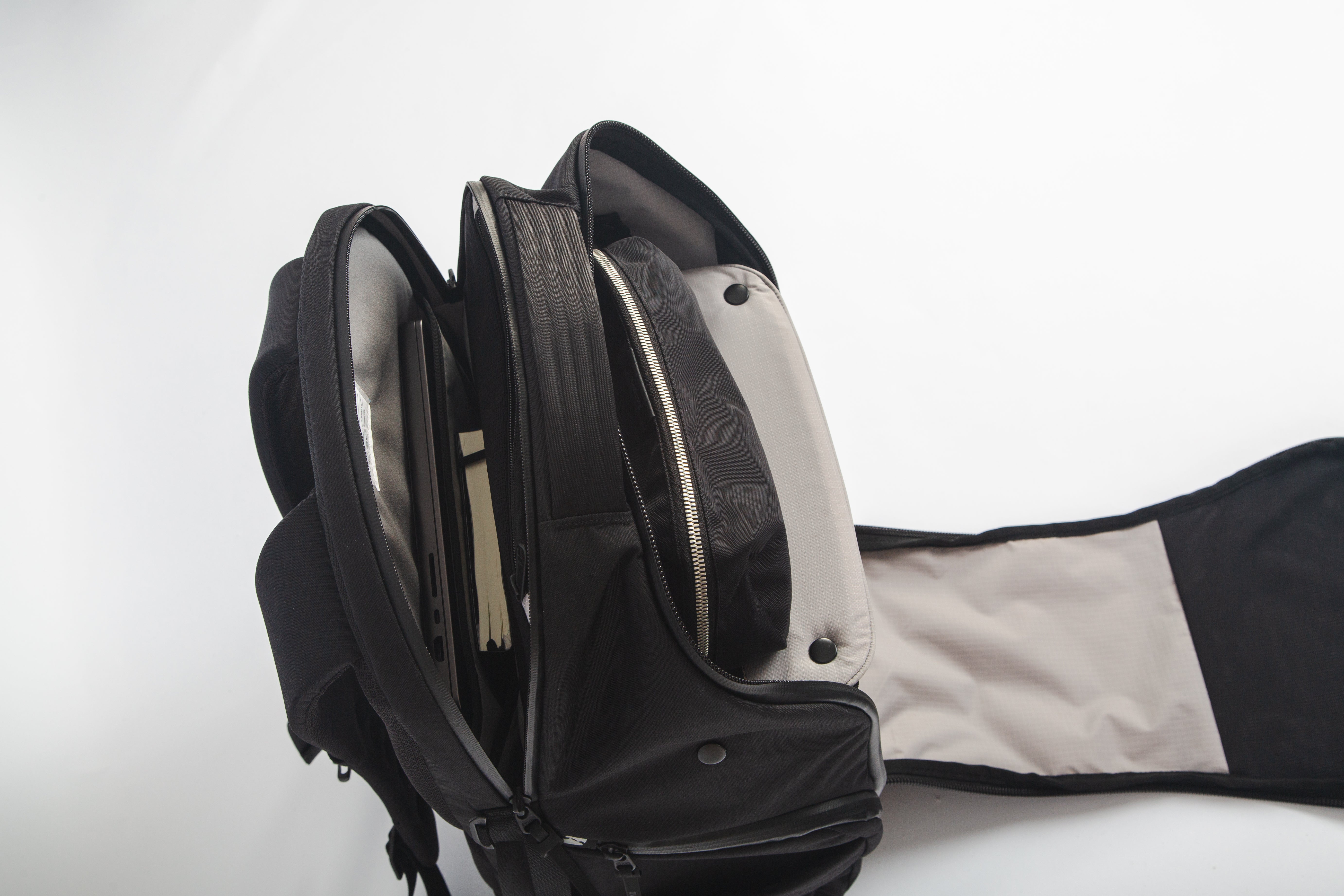 Upper zippers of DVRGE backpack opened to display laptop compartment and shelf divider 